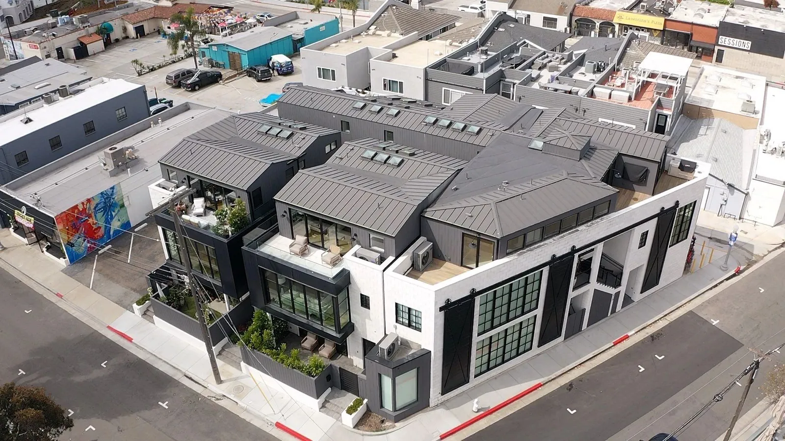 Modern coastal home with dark standing seam metal roof, drone view